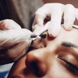 Closeup of a beautician hands microblading eyebrows to model.
